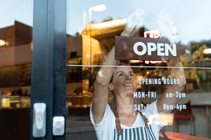 business owner hanging open sign on business door