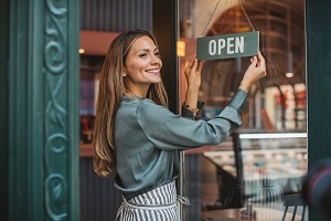 business owner turning open sign on door