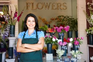woman standing outside flower shop smiling at camera