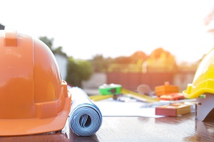 orange hard hat with blue prints and other tools on a table